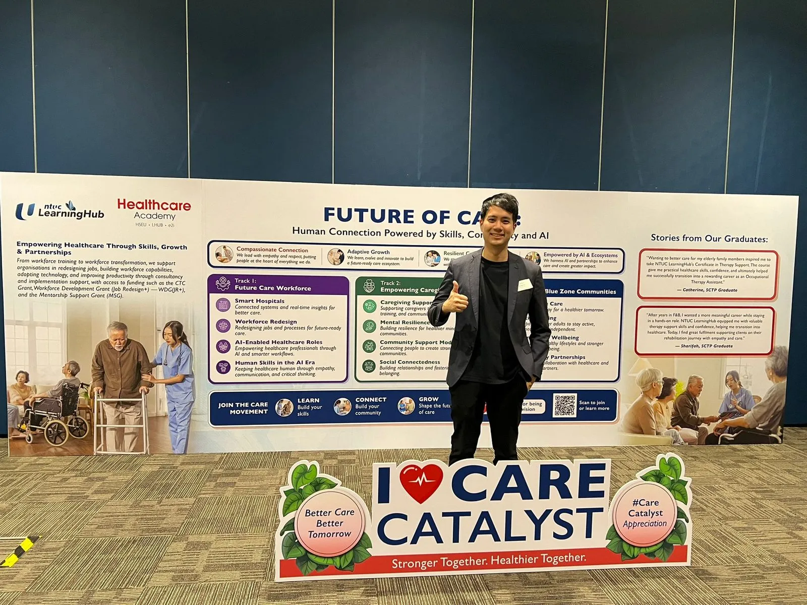 Yau Png Ow standing in front of the Future of Care event banner and Care Catalyst display