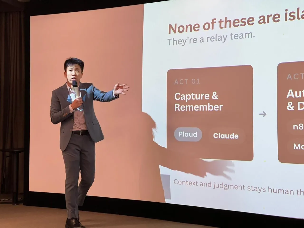 A facilitator presenting a slide that reads "None of these are islands. They're a relay team", mapping AI tools across capture, automation and human judgement.