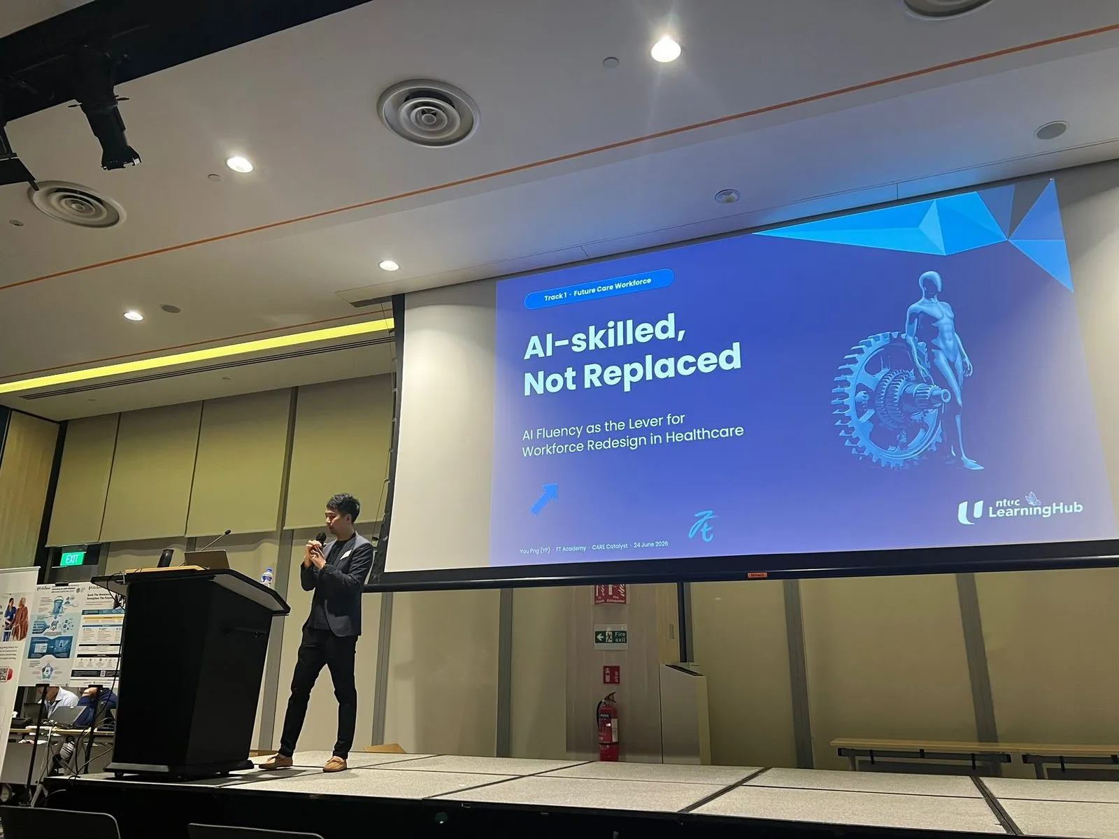 Yau Png Ow on stage presenting "AI-skilled, Not Replaced: AI Fluency as the Lever for Workforce Redesign in Healthcare" at the NTUC LearningHub Healthcare Sector event